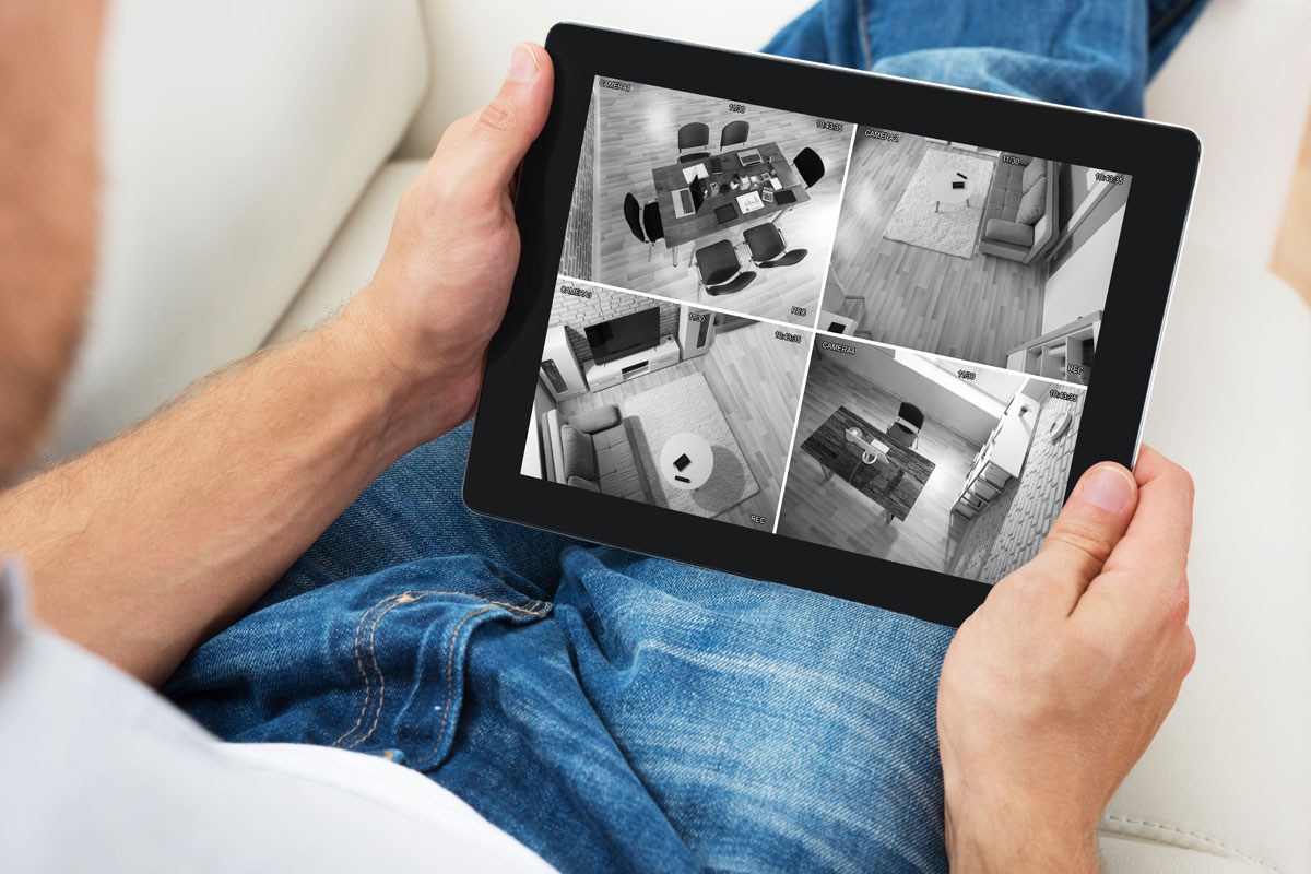Man viewing home security camera feeds on a tablet