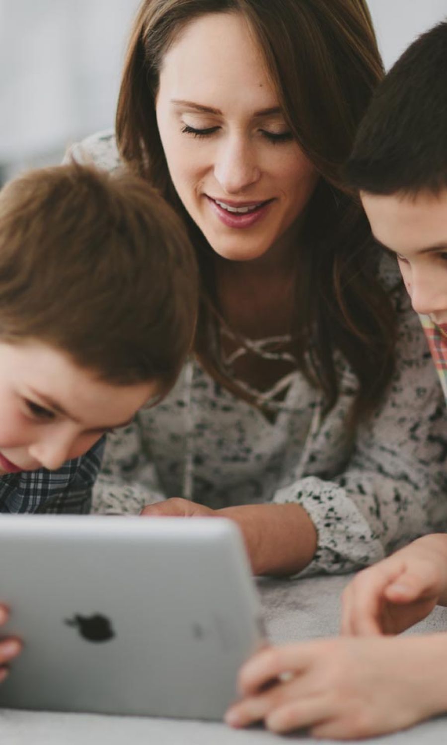 Woman and her kids looking at an ipad together
