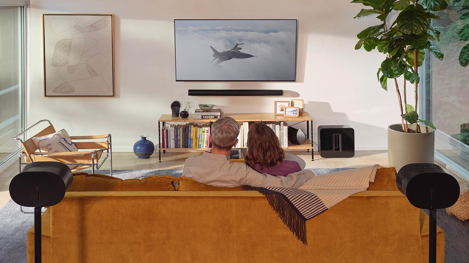 Middle-aged couple watching TV with Sonos Era 300 Speakers on the front